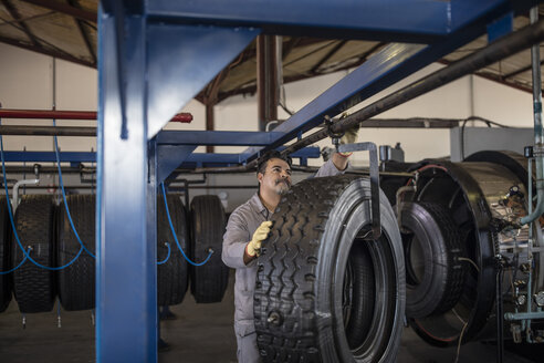 Reifenreparateur hängt neuen Reifen an den Haken - ZEF11159