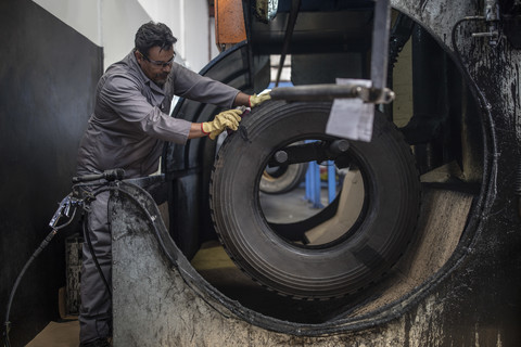 Reparateur bei der Arbeit an einem Reifen in einer Fabrik, lizenzfreies Stockfoto
