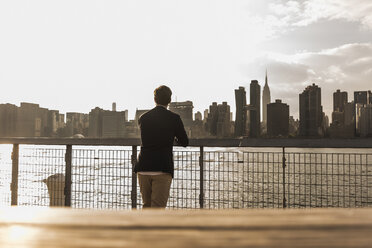 USA, New York City, back view of businessman looking at skyline of Manhattan - UUF08844