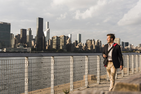 USA, New York City, Geschäftsmann geht am East River entlang, lizenzfreies Stockfoto