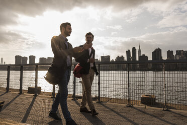 USA, New York City, zwei Geschäftsleute gehen am East River entlang - UUF08848