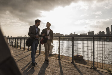 USA, New York City, two businessmen walking along East River - UUF08849