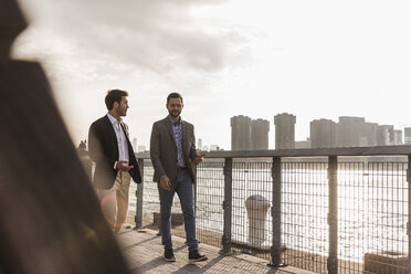 USA, New York City, two businessmen walking along East River - UUF08850