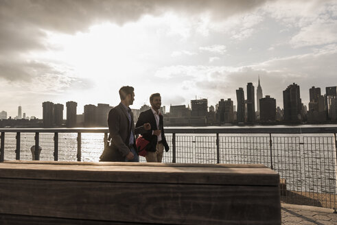 USA, New York City, zwei Geschäftsleute gehen am East River entlang - UUF08851