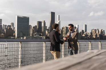 USA, New York City, two businessmen talking at East River - UUF08855