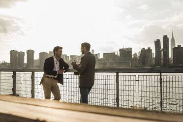 USA, New York City, two businessmen talking at East River - UUF08856