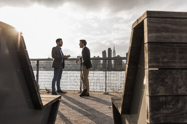 USA, New York City, two businessmen talking at East River - UUF08857