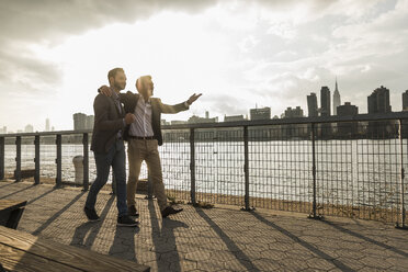 USA, New York City, zwei Geschäftsleute gehen gemeinsam am East River entlang - UUF08859