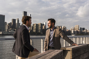USA, New York City, two businessmen talking at East River - UUF08860