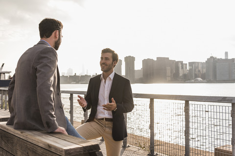 USA, New York City, zwei Geschäftsleute im Gespräch am East River, lizenzfreies Stockfoto