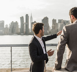 USA, New York City, businessman talking to colleague at East River - UUF08862