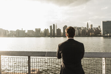 USA, New York City, back view of businessman looking at skyline of Manhattan - UUF08868