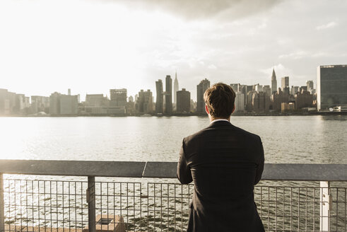 USA, New York City, Rückenansicht eines Geschäftsmannes mit Blick auf die Skyline von Manhattan - UUF08868