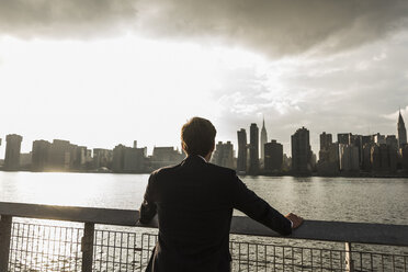 USA, New York City, Rückenansicht eines Geschäftsmannes mit Blick auf die Skyline von Manhattan - UUF08869