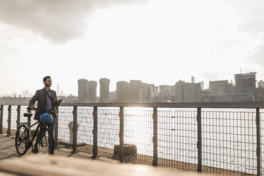 USA, New York City, businessman with bicycle walking along East River - UUF08871