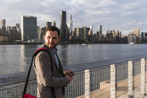 USA, New York City, Geschäftsmann am East River, der sich umschaut, lizenzfreies Stockfoto