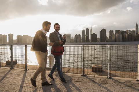 USA, New York City, zwei junge Männer gehen am East River entlang, lizenzfreies Stockfoto