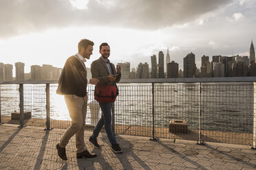 USA, New York City, two young men walking along East River - UUF08896