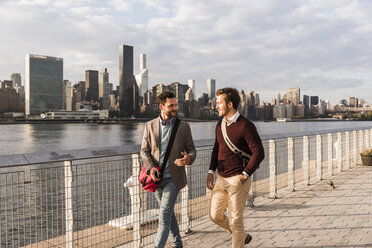 USA, New York City, two young men walking along East River - UUF08897