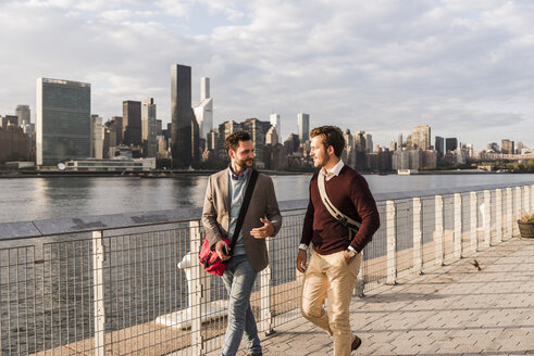 USA, New York City, zwei junge Männer gehen am East River entlang - UUF08897