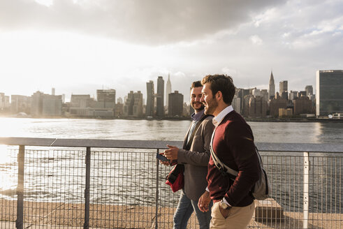 USA, New York City, zwei junge Männer gehen am East River entlang - UUF08898