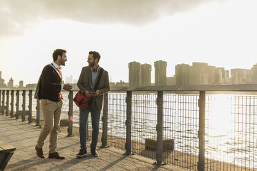 USA, New York City, zwei junge Männer gehen am East River entlang - UUF08899