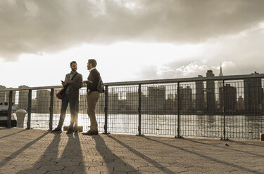 USA, New York City, zwei junge Männer unterhalten sich am East River - UUF08902