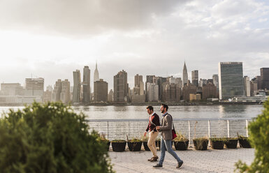 USA, New York City, zwei junge Männer gehen am East River entlang - UUF08904