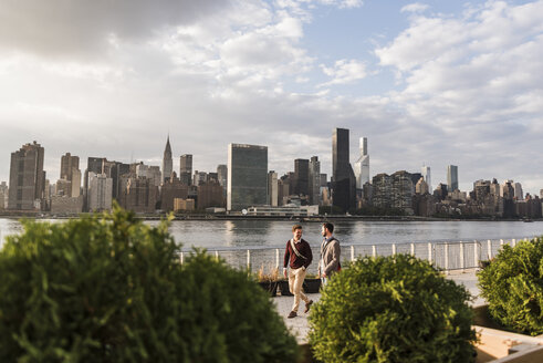 USA, New York City, zwei junge Männer gehen am East River entlang - UUF08906