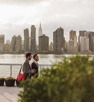 USA, New York City, zwei junge Männer gehen am East River entlang - UUF08907