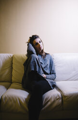 Portrait of lonely woman sitting on the couch at night - JRFF00989