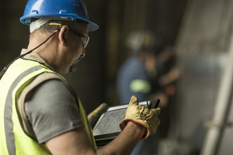 Ingenieur sieht sich einen Bauplan auf einem digitalen Tablet an, lizenzfreies Stockfoto