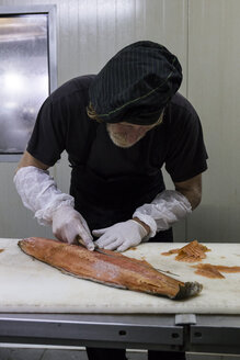 Fischräucherer, der frisch geräucherten Lachs mit einem Messer säubert - ABZF01459