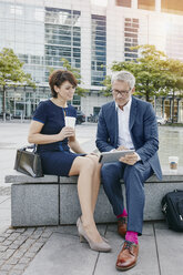 Businessman and businesswoman with digital tablet outdoors - RORF00390