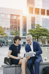 Businessman and businesswoman with digital tablet outdoors - RORF00391