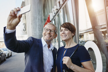 Businessman and businesswoman taking a selfie outdoors - RORF00411