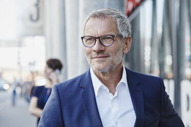 Confident businessman outdoors with woman in background - RORF00414