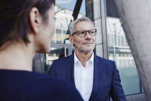 Businessman with businesswoman outdoors looking sideways - RORF00421