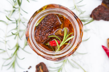Glass of pickled dried tomatoes with rosemary and peperoncino, close-up - LVF05541