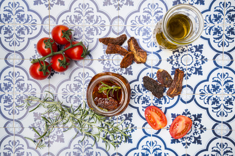 Glas mit eingelegten getrockneten Tomaten und Zutaten auf Fliesen, lizenzfreies Stockfoto