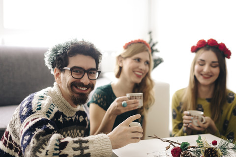 Porträt eines lächelnden Mannes, der sich mit Freunden zur Weihnachtszeit entspannt, lizenzfreies Stockfoto