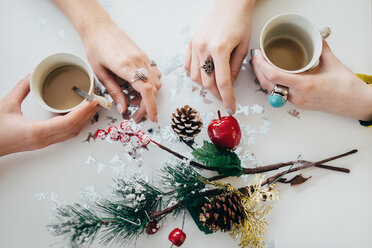 Hände von zwei Frauen mit Kaffeetassen auf einem Tisch mit Weihnachtsdekoration - LCUF00075