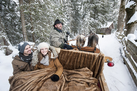 Ein Paar genießt eine Fahrt in einem Pferdeschlitten im Winter, lizenzfreies Stockfoto