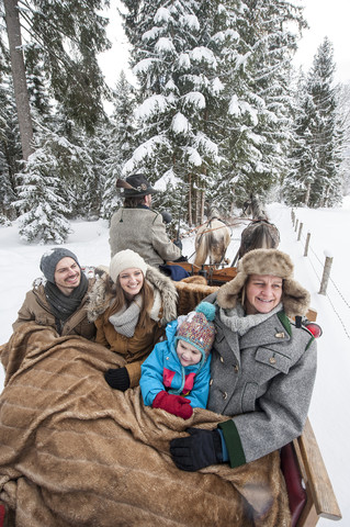 Eine Familie genießt eine Fahrt mit dem Pferdeschlitten im Winter, lizenzfreies Stockfoto