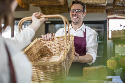 Lächelnder Lebensmittelhändler bedient Kunden in einem Hofladen, lizenzfreies Stockfoto