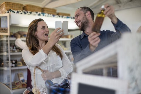 Glückliches Paar, das im Hofladen mit dem Smartphone fotografiert, lizenzfreies Stockfoto
