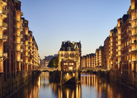 Deutschland, Hamburg, Speicherstadt, beleuchtete Altbauten mit Elbphilharmonie im Hintergrund - WHF00059