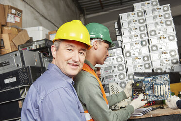 Arbeiter in einer Computer-Recyclinganlage zerlegen ein Motherboard - RKNF00402