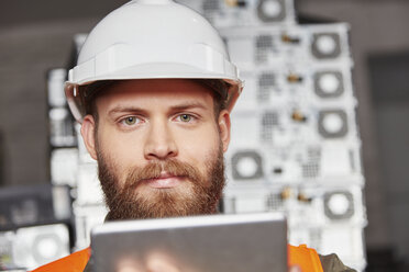 Worker in computer recycling plant using digital tablet - RKNF00403