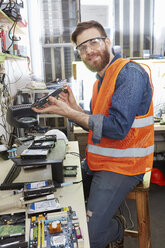 Arbeiter in einer Computer-Recyclinganlage beim Zerlegen einer Festplatte - RKNF00424